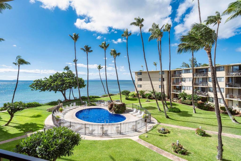 an aerial view of a resort with a swimming pool and palm trees at Kanai a Nalu 314 - Newly Renovated, Oceanfront, AC in Wailuku