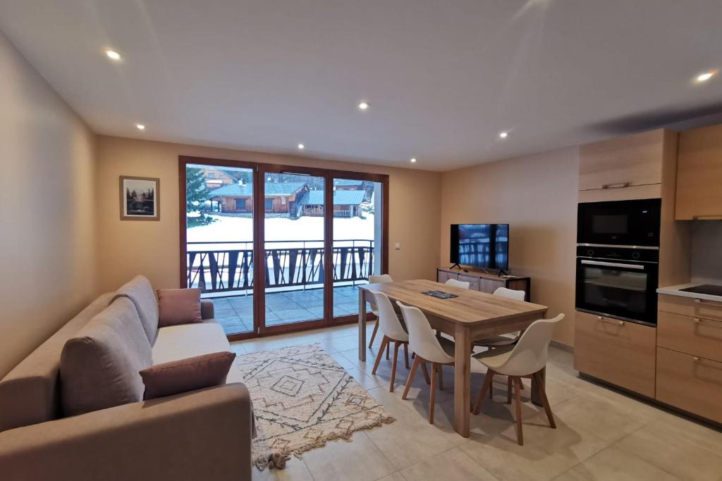 a living room with a couch and a table with chairs at L'écrin des neiges - Sauna in La Féclaz