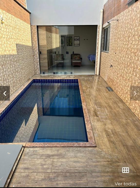 una piscina con azulejos azules en el suelo y una casa en Hospedagem aconchegante com área gourmet, en Araguaína