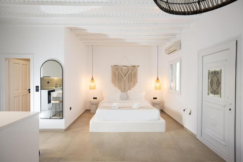 a white bedroom with a bed and a mirror at Loom Suite Ornos in Mýkonos City