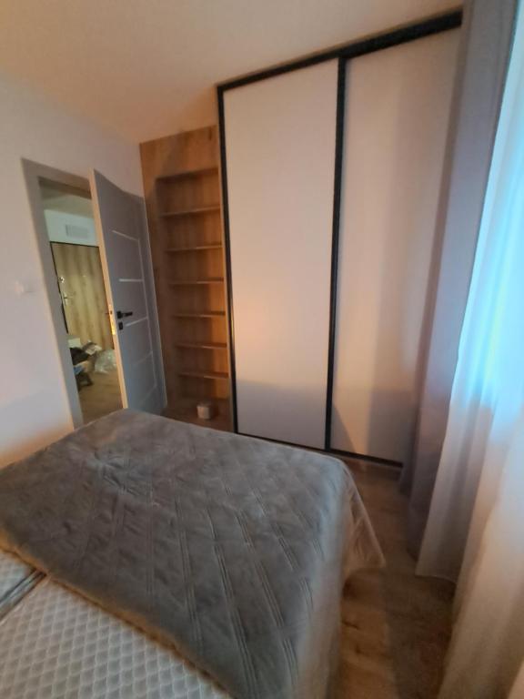 a bedroom with a bed and a large glass door at Apartament Drwęcka in Ostróda