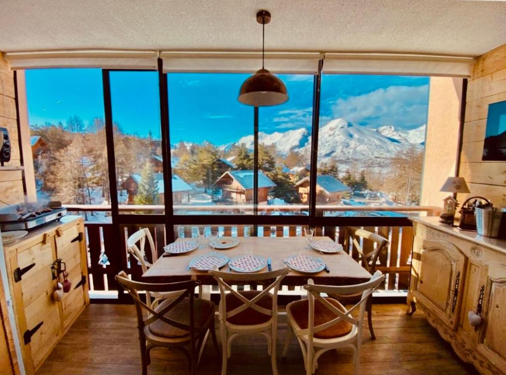 einen Tisch und Stühle in einer Küche mit einem großen Fenster in der Unterkunft Appart 5pers joue du loup pied de pistes vue top in La Joue du Loup