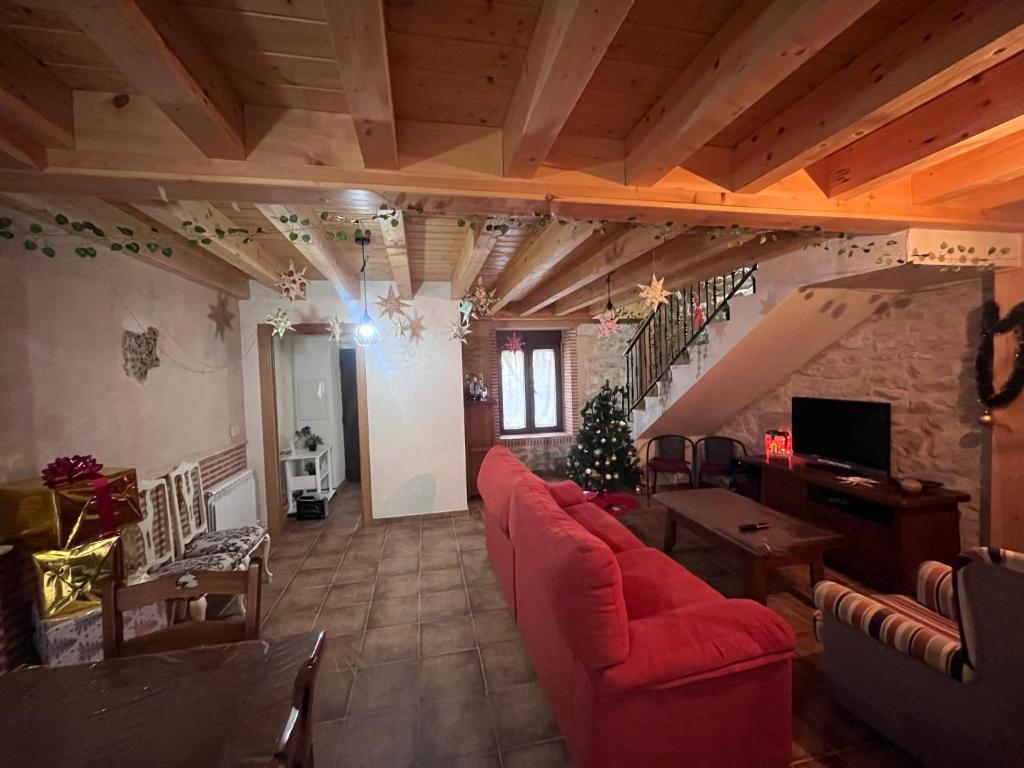 sala de estar con sofá rojo y árbol de Navidad en Casa Marite Vivienda de uso turístico en Campillo de Aranda