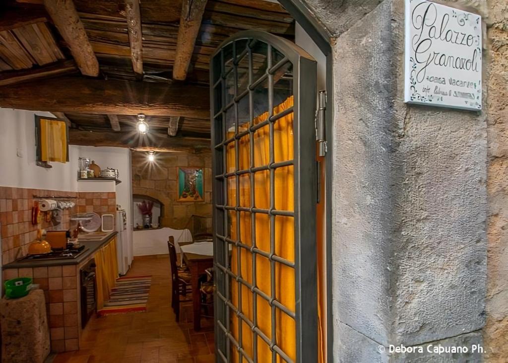 eine offene Tür zu einer Küche mit einem Tisch in der Unterkunft Palazzo Granaroli in Bagnoregio
