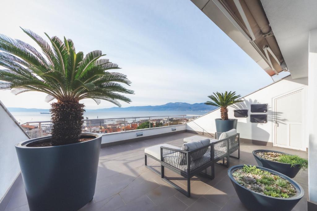 a balcony with chairs and a palm tree on a building at Penthouse Belvedere City View with Private Parking in Rijeka