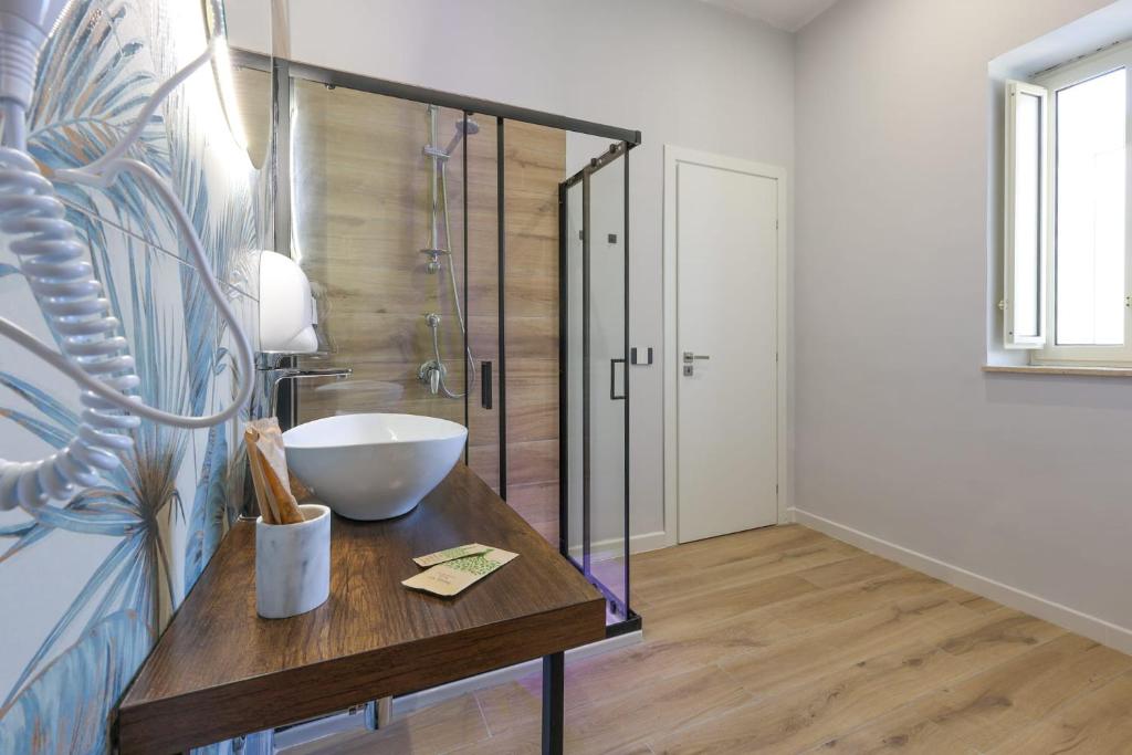 a bathroom with a glass shower and a wooden table at Cuore Napoli Centro in Naples