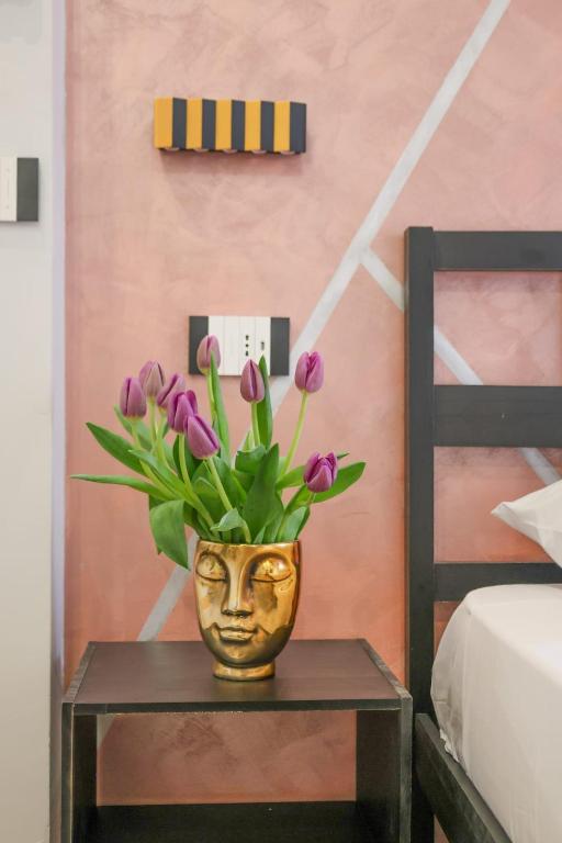 a vase with purple flowers on a table next to a bed at Cuore Napoli Centro in Naples