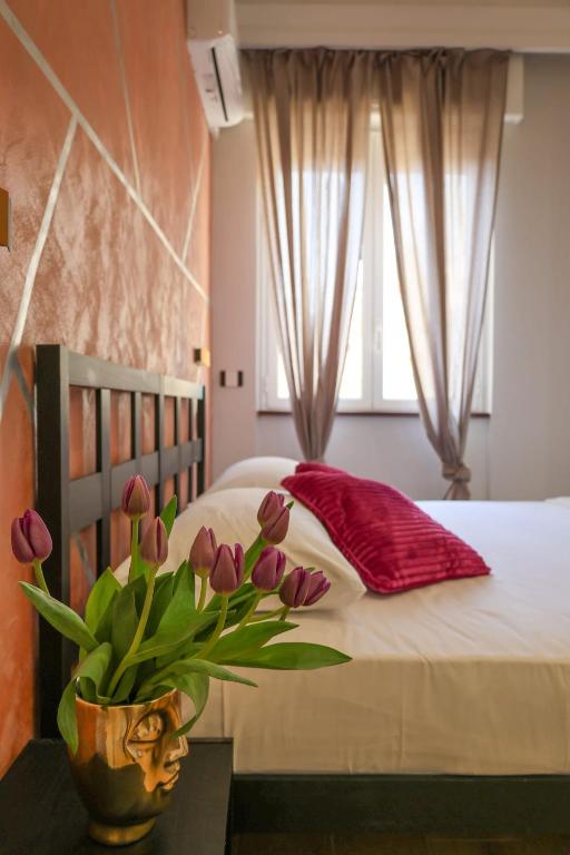 a bedroom with a bed with a vase of flowers on a table at Cuore Napoli Centro in Naples