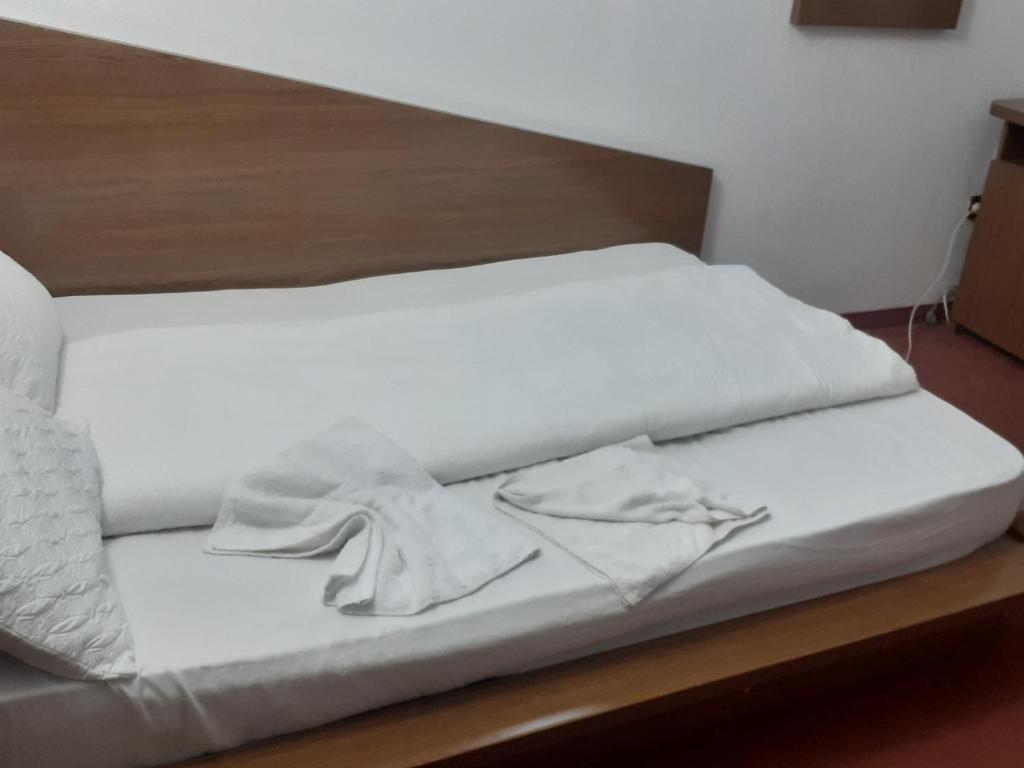 a bed with white sheets and a wooden headboard at Hanul Anitei La paducel 