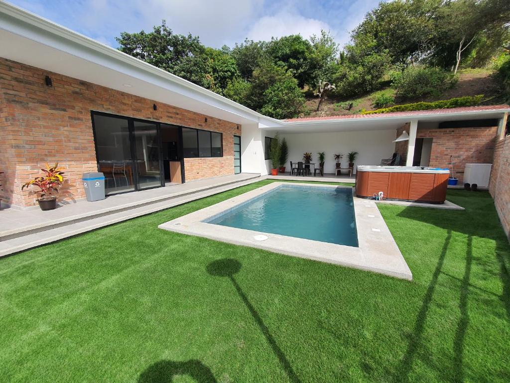 un patio trasero con piscina y césped verde en Viento Susurrante, en Santa Isabel
