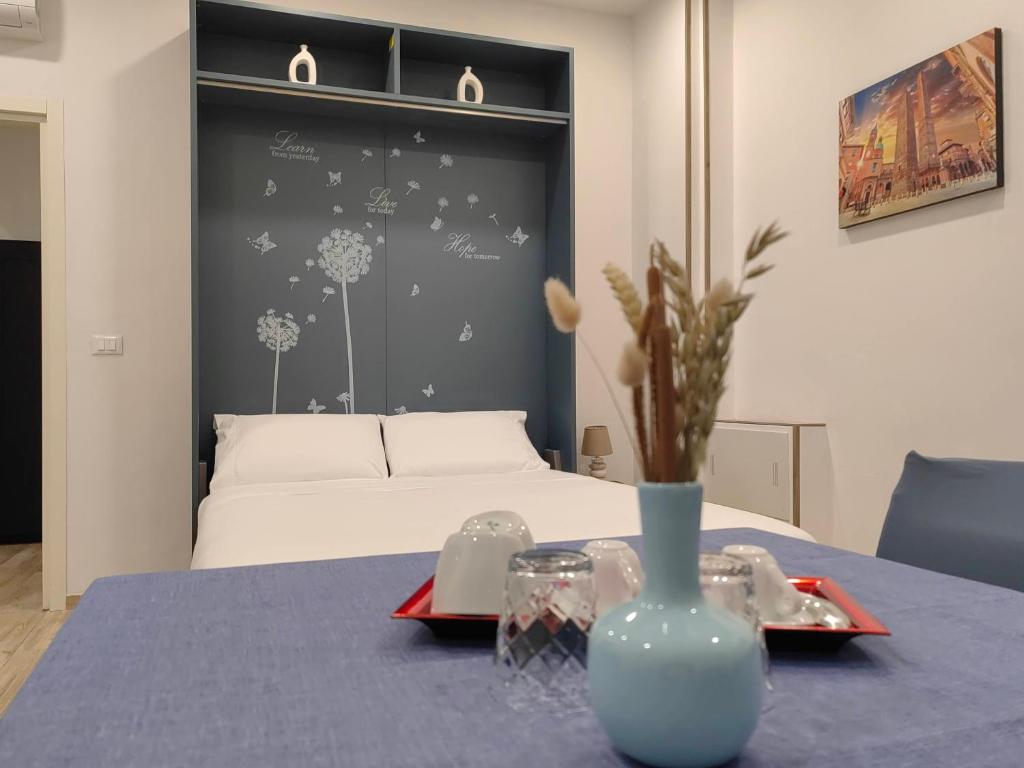 Un dormitorio con una cama y una mesa con un jarrón. en PIGRO House - Bologna Airport Suite en Bolonia