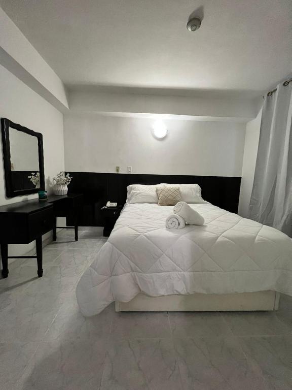 ein Schlafzimmer mit einem großen weißen Bett und einem Schreibtisch in der Unterkunft HOTEL BLUE COSTA Panama in Panama-Stadt