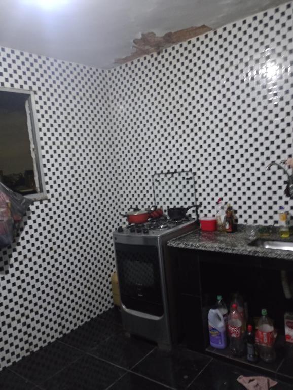 a kitchen with a stove and a tiled wall at Casa Penha in Rio de Janeiro