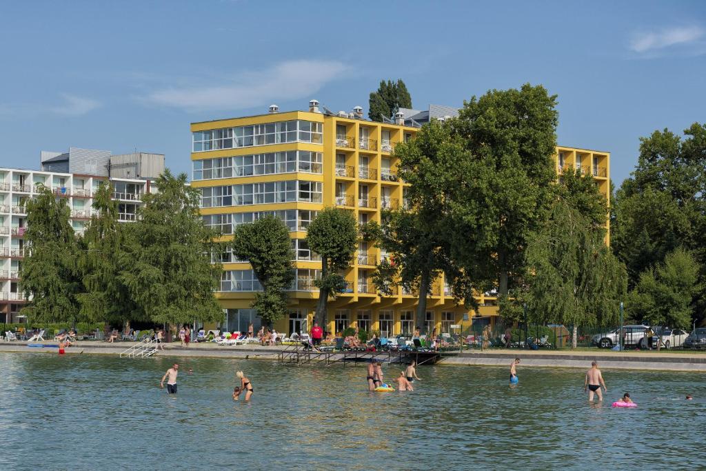 un grupo de personas en el agua frente a un edificio en Hotel Lido, en Siófok