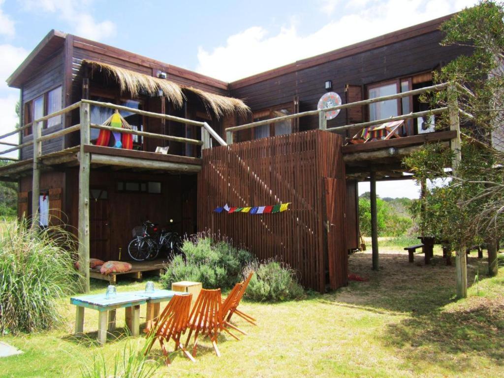 a house with chairs and a table in front of it at Rico Pino eco posada in La Pedrera