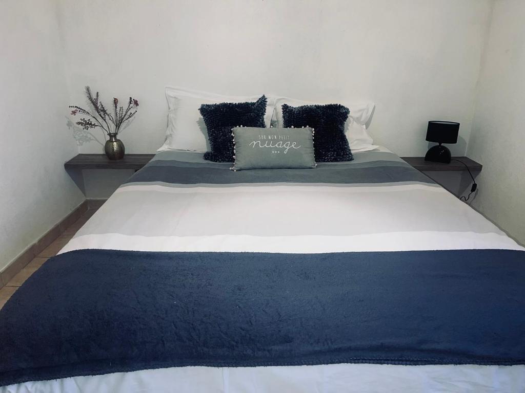 ein großes Bett mit blauer und weißer Bettwäsche und Kissen in der Unterkunft Appartement à 2 mins du centre in Sarlat-la-Canéda