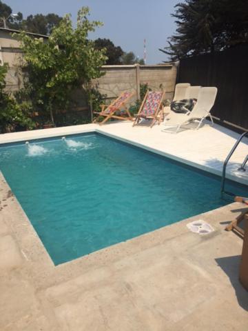 a swimming pool with two lawn chairs next to it at Casa isla Negra in Isla Negra