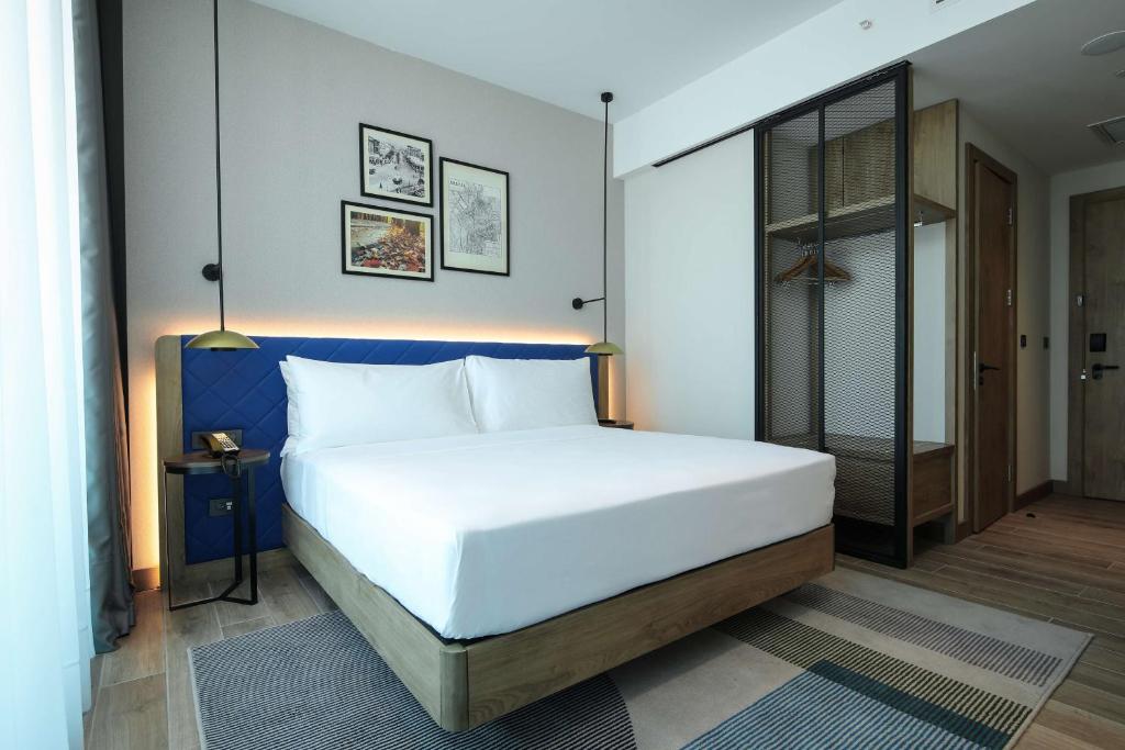 Schlafzimmer mit einem großen weißen Bett mit blauem Kopfteil in der Unterkunft Hilton Garden Inn Ankara Dikmen in Ankara