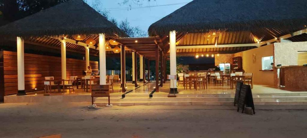 a restaurant with tables and chairs and umbrellas at night at Villa Penyu Gili Trawangan in Gili Trawangan