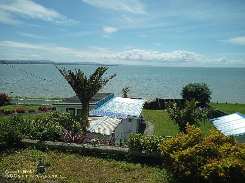 una casa con pannelli solari e l'oceano sullo sfondo di Clarks beach batch snatch ad Auckland