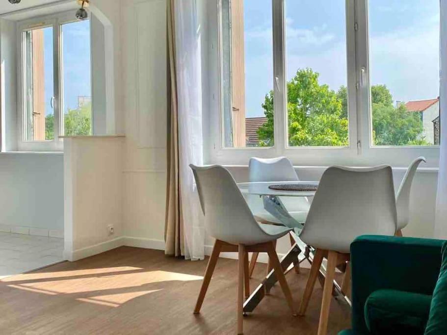 uma sala de jantar com mesa, cadeiras e janelas em 2 bedrooms, 15min from Paris, free parking em Deuil-la-Barre