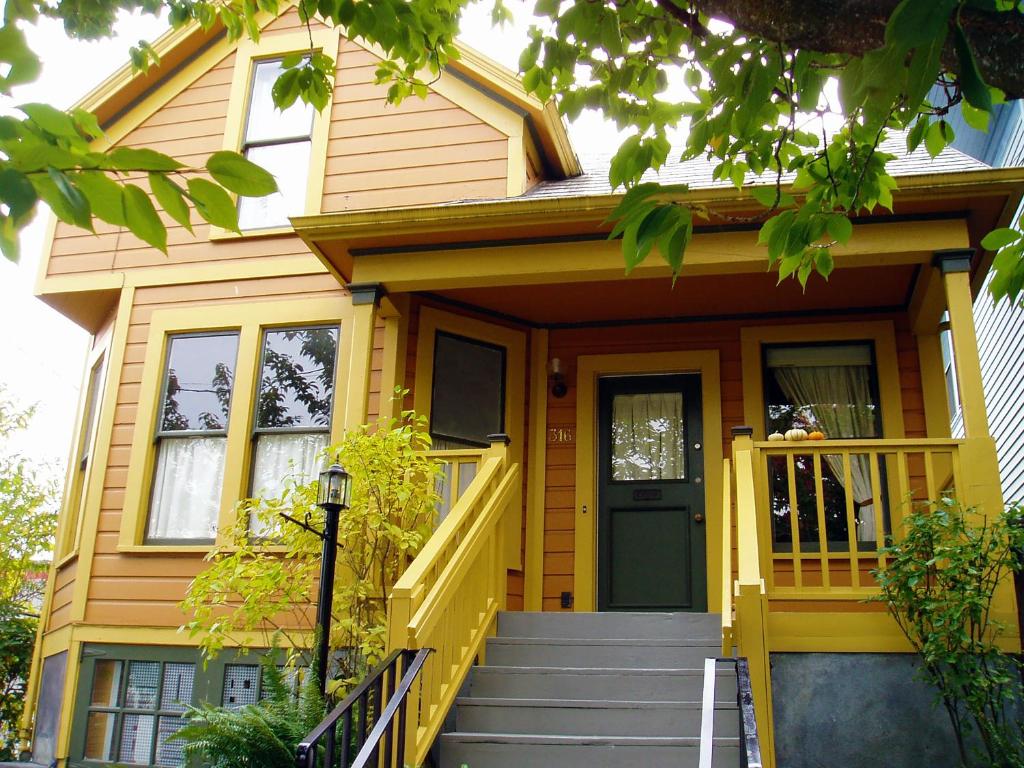 a yellow house with a yellow door and stairs at NE Portland Oregon Modern Victorian Duplex in Portland
