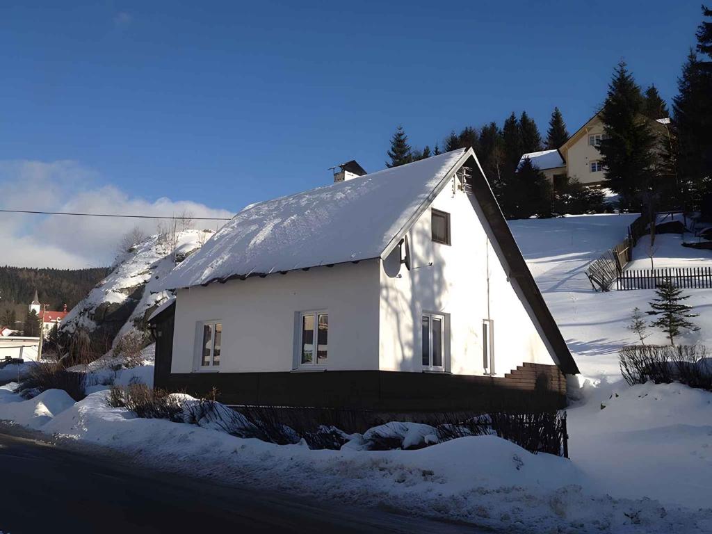 Holiday home Nove Hamry/Erzgebirge 1646 في Nové Hamry: بيت أبيض صغير عليه ثلج