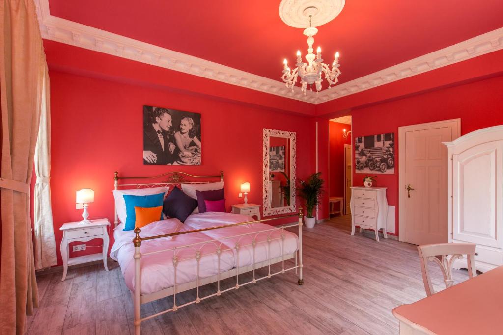 1 dormitorio con paredes rojas y 1 cama con lámpara de araña. en Grande Albergo Giancarlo en Weimar