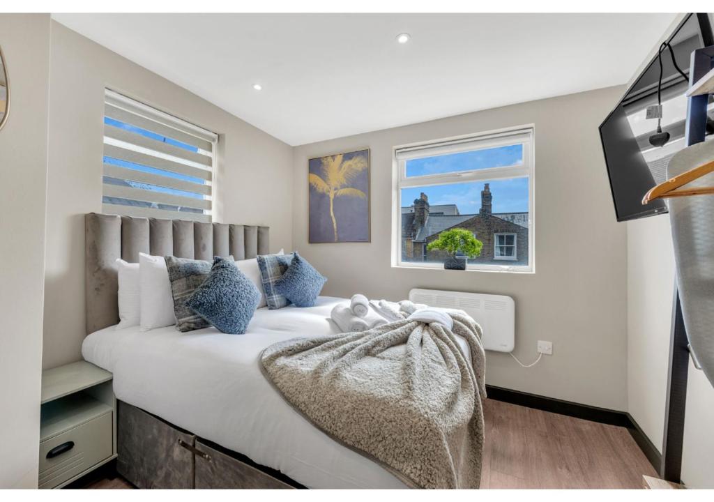 una camera da letto con un grande letto bianco con cuscini blu di A Place to Dream: Airy Studio in Serene Locale a Londra