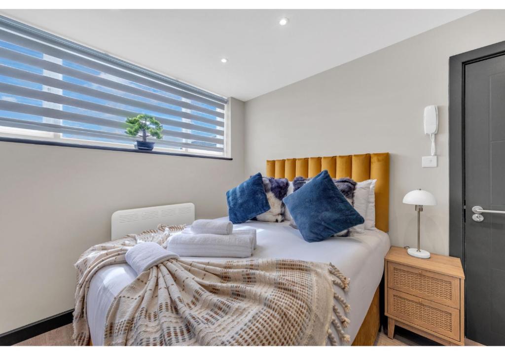 Un dormitorio con una cama con almohadas azules y una ventana en Get Your Zen On: Relaxing Studio in Central, en Londres