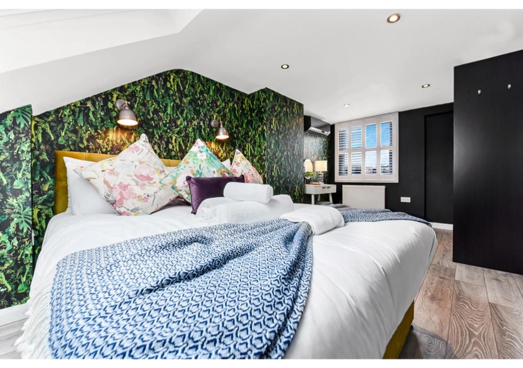 a bedroom with a large white bed with a blue blanket at Earth Tones & Greenery: 4BR Flat Sleeps 8 in London
