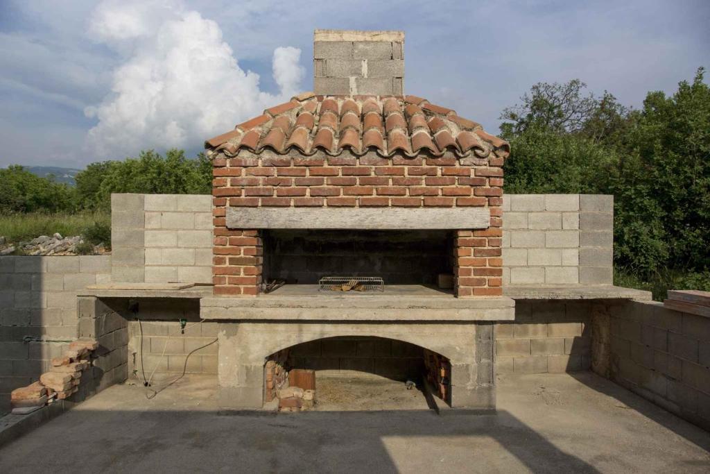 um forno de pizza de tijolos ao ar livre com um tijolo em Apartments in Novi Vinodolski 15349 em Novi Vinodolski