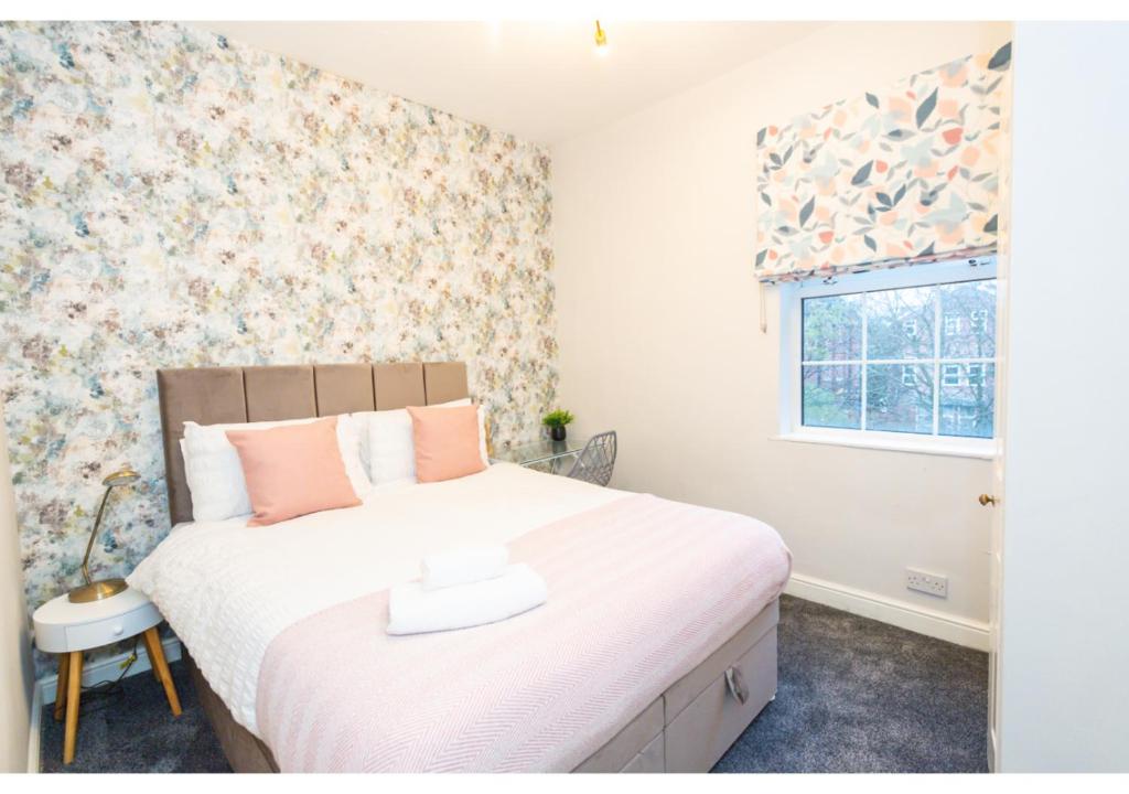 a bedroom with a large bed with pink pillows and a window at Fresh and Relaxing 1 BD Flat in Manchester