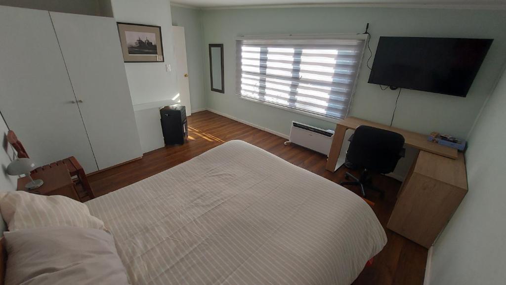 a bedroom with a bed and a flat screen tv at Camino de Luna, amplio y cómodo espacio in Valdivia