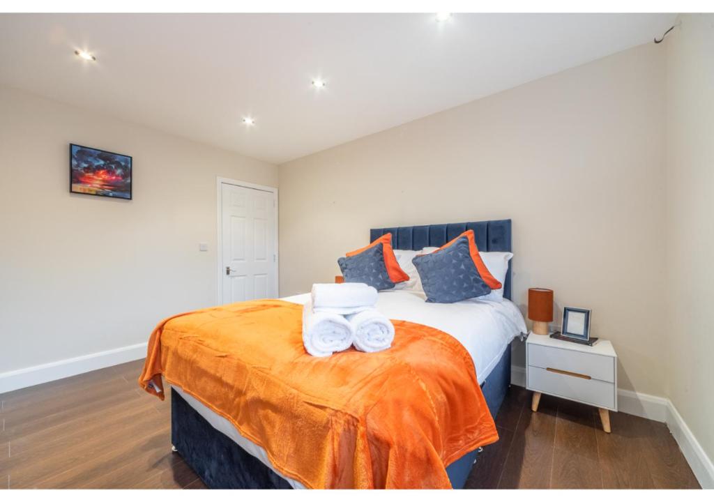 2 Bedroom Apartment in Perfect Location في Enfield Lock: غرفة نوم مع سرير مع منشفتين على بطانية برتقالية