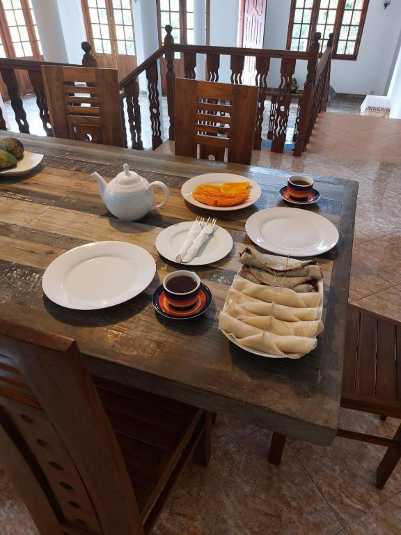 a wooden table with plates of food and a teapot at Mystique Hideout in Kandy