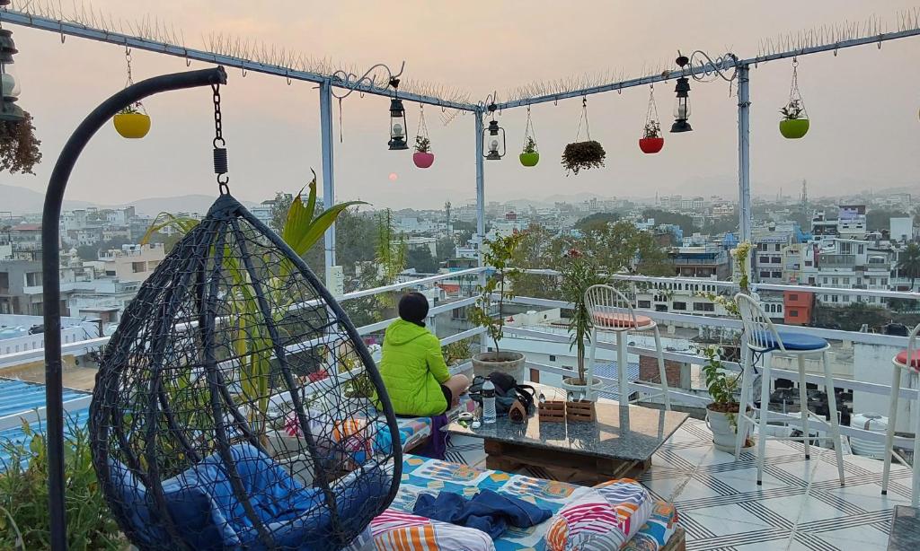 una persona sentada en una mesa en un balcón en Raahi Backpacker's Hostel, en Udaipur