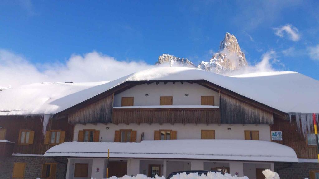 un bâtiment recouvert de neige avec une montagne en arrière-plan dans l'établissement Apartment in Passo Rolle/Südtirol 23444, à Passo Rolle