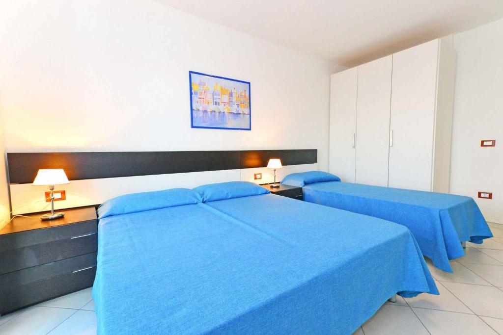 リニャーノ・サッビアドーロにあるApartments in Lignano 21649のベッドルーム(ブルーシーツ付)のベッド2台