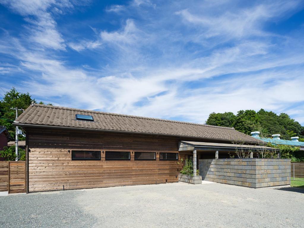 een groot houten gebouw met een dak bij HATAYA Cafe&Hostel in Kyotango