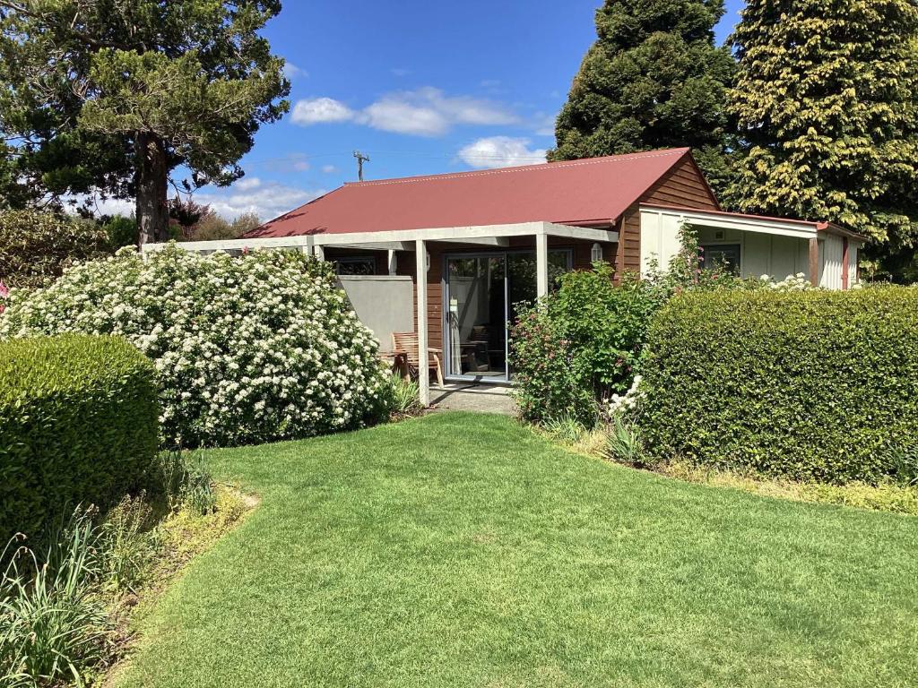 a small house with a red roof and a yard at Hanmer Garden Suites in Hanmer Springs