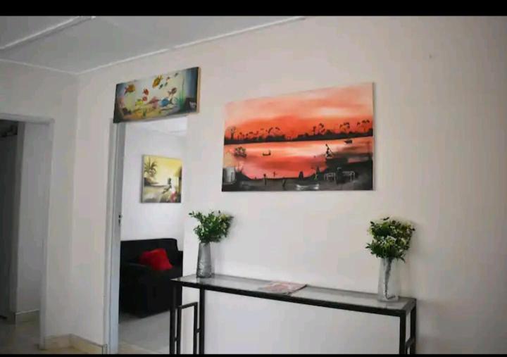 a table in a room with a painting on the wall at House of Joy in Lilongwe