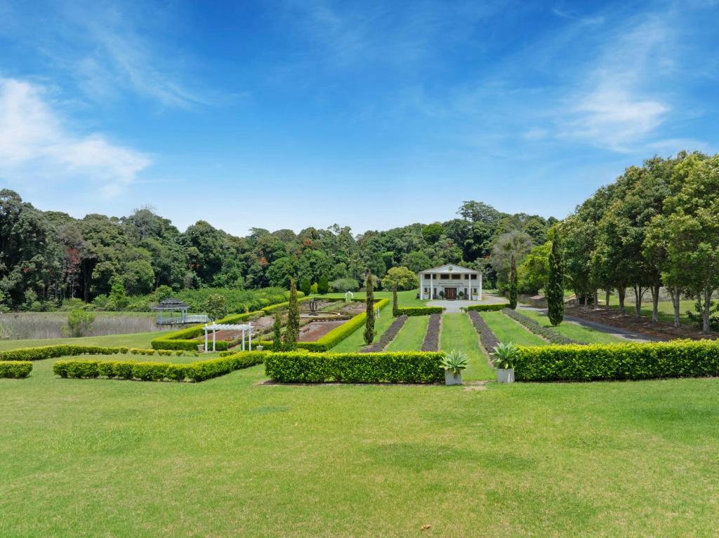a garden with a white house in the distance at lavender cottage three large bedroom house in Mount Tamborine