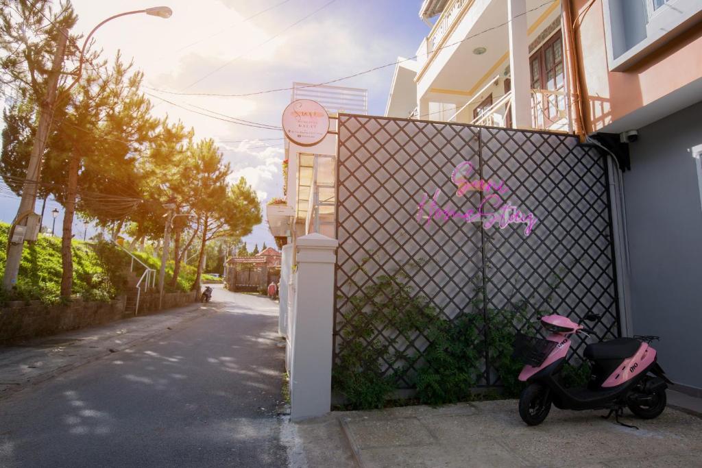 大叻的住宿－Suri Homestay，停在围栏旁的粉红色摩托车