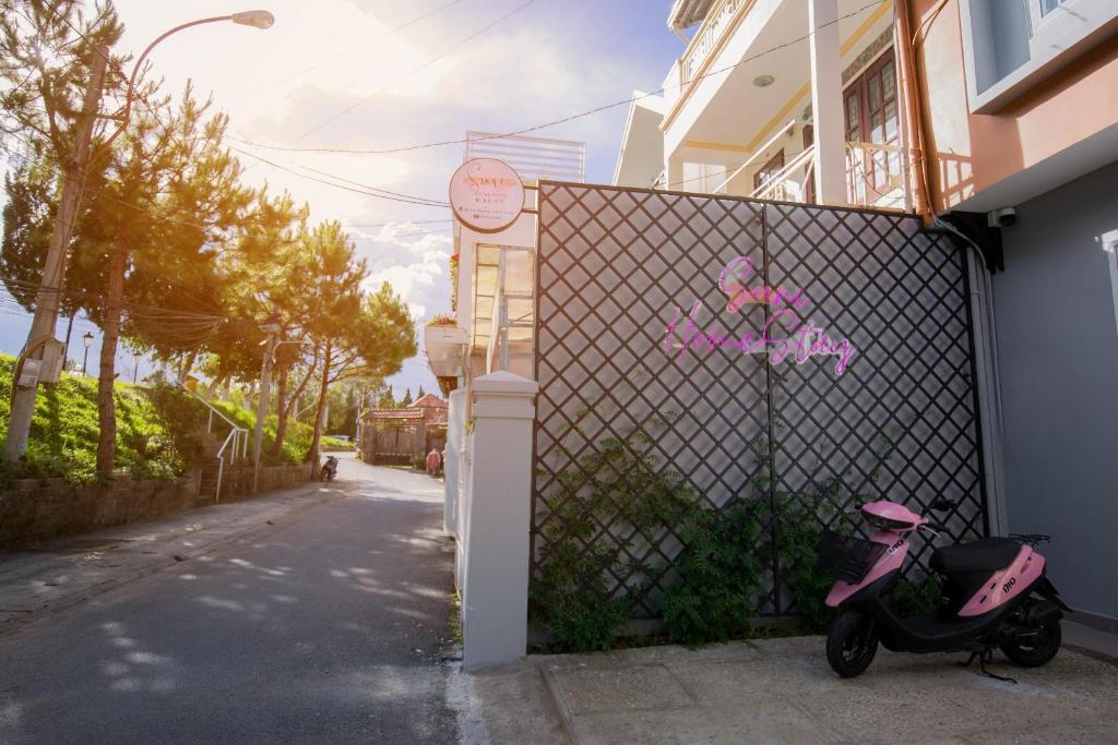 una moto rosa estacionada junto a una valla en Suri Homestay en Da Lat