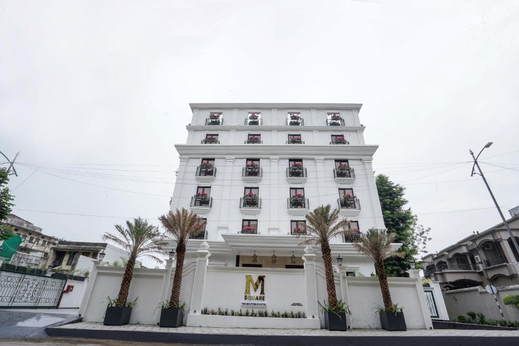 un edificio blanco con palmeras delante en M2 Square by Monday Premium en Nagpur