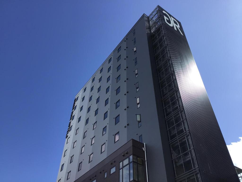 un edificio alto con el logo de cst en él en Green Rich Hotel Tokuyama Ekimae, en Shunan