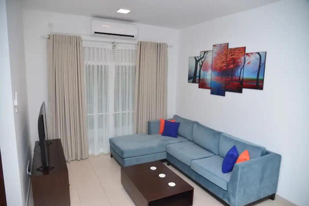a living room with a blue couch and a tv at Cozy 2 bed 1 bath Apartment for rent in Homagama