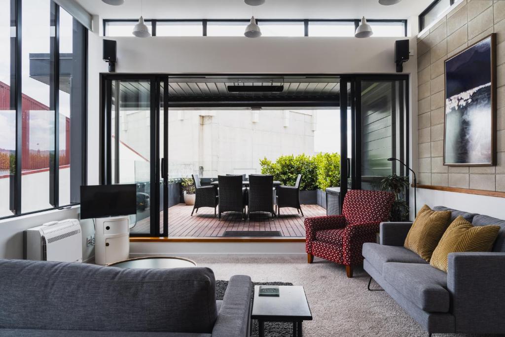 a living room with couches and chairs and a patio at New York Loft in Dunedin