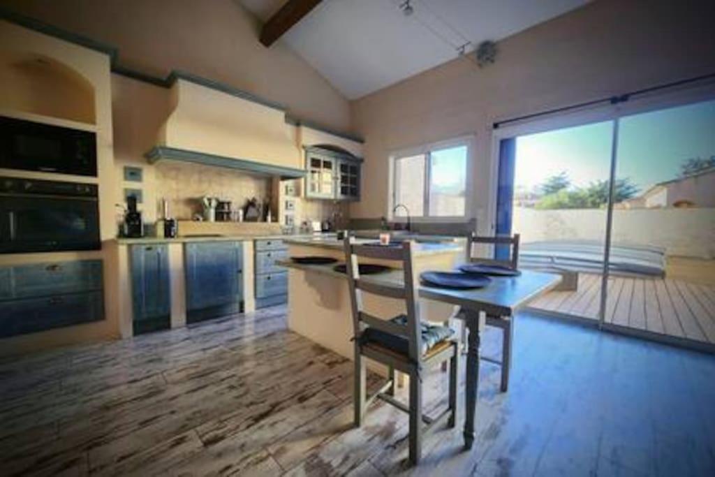 a large kitchen with a table and chairs in it at Jolie Maison Jardin Piscine in Narbonne